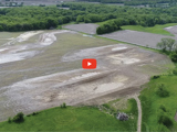image of waterway next to green grass and fields and a red video play button