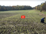 image of farm field with farmer working and red video play button