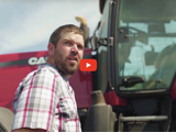 image of farmer wearing a red plaid shirt standing next to a red tractor and red video play button