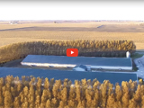 image of a farm showing a tree buffer and a red video play button